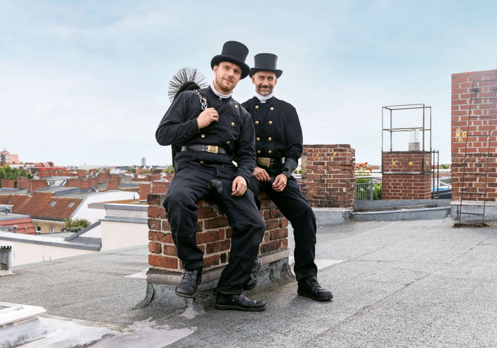 Schornsteinfeger sitzen auf einem Schornstein auf dem Dach