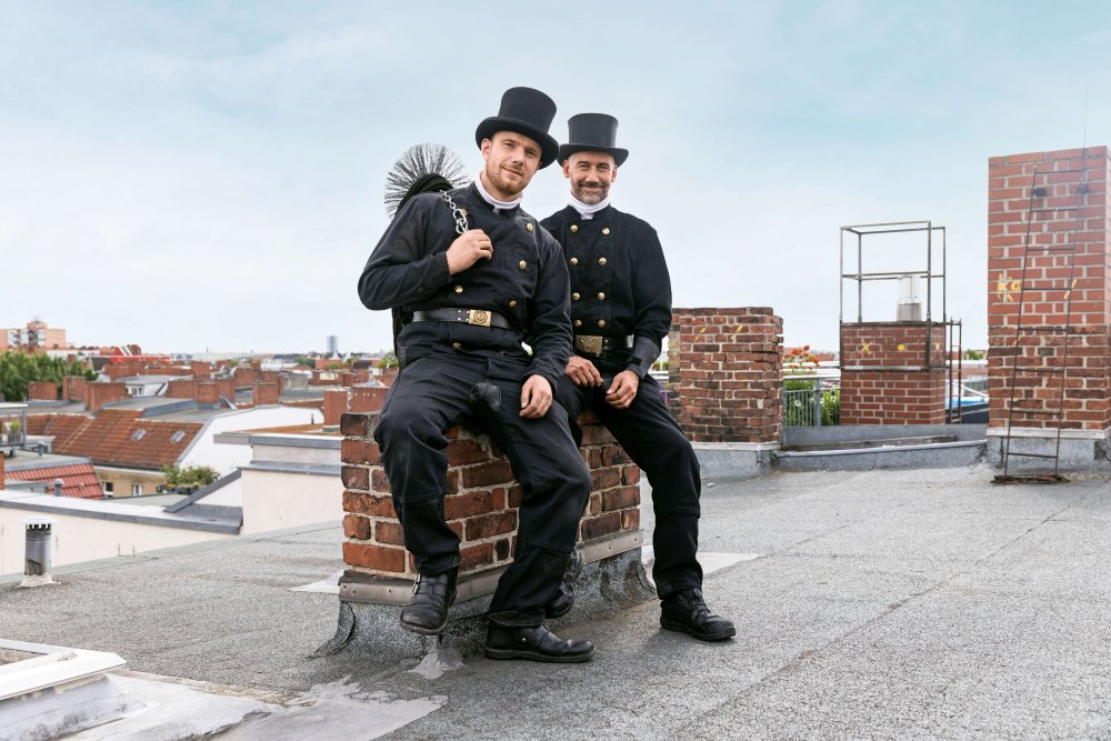 Schornsteinfeger sitzen auf einem Schornstein auf dem Dach